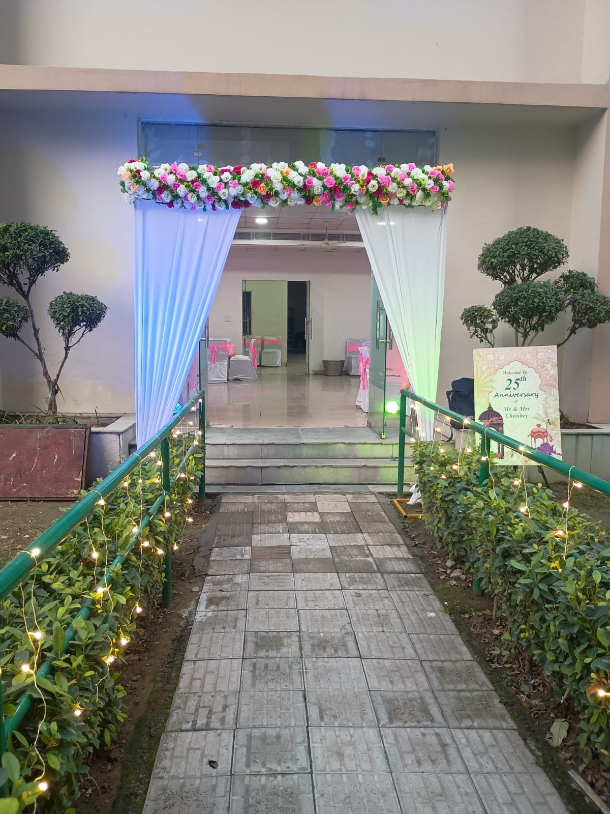 25th Anniversary Floral Entrance Decoration With White Drapes And Pink Flowers - anniversary room decoration by ARV Decor