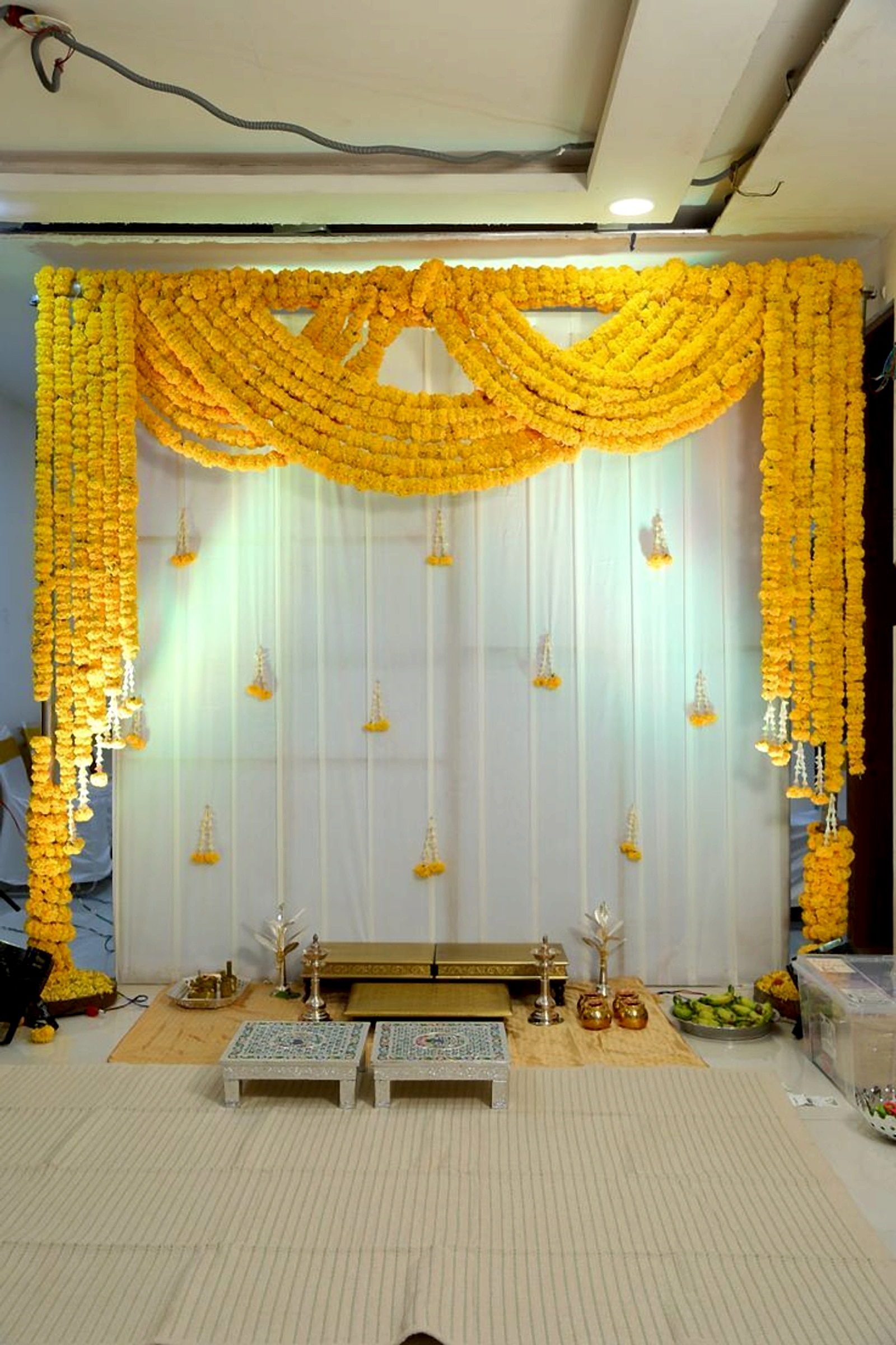 Traditional Pooja Decoration With Marigold Floral Garlands And White Backdrop - Housewarming by ARV Decor thumbnail 2